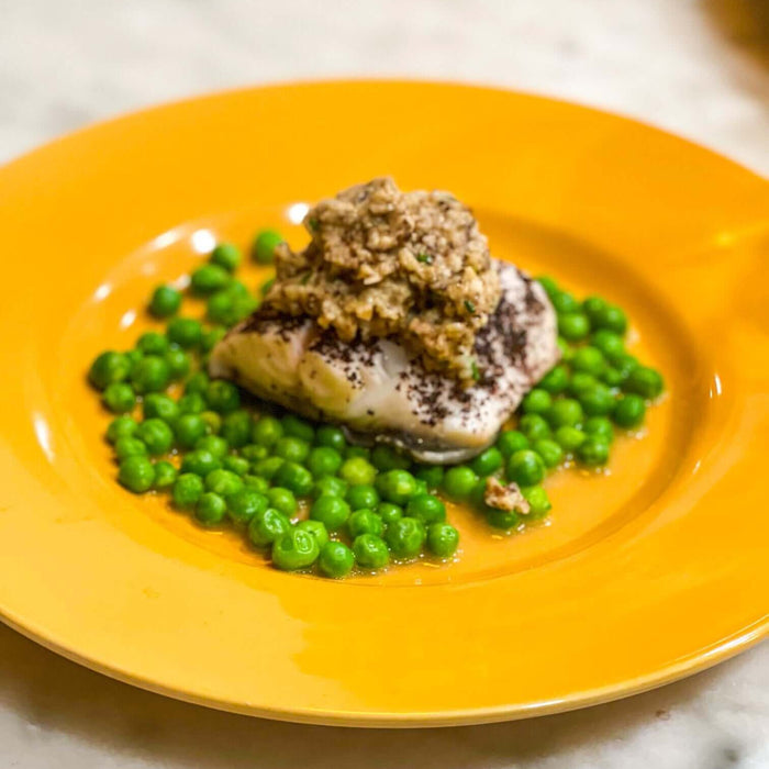 Springy Black Cod Recipe served with green peas on an orange plate, showcasing a delicious seafood dish.