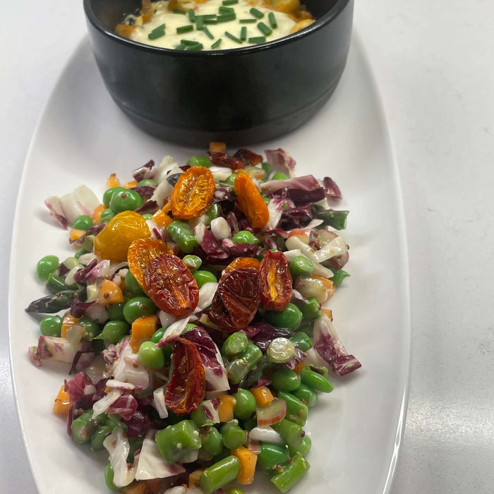 Colorful vegetarian spring dinner recipe featuring fresh vegetables and a baked dish in a black bowl.