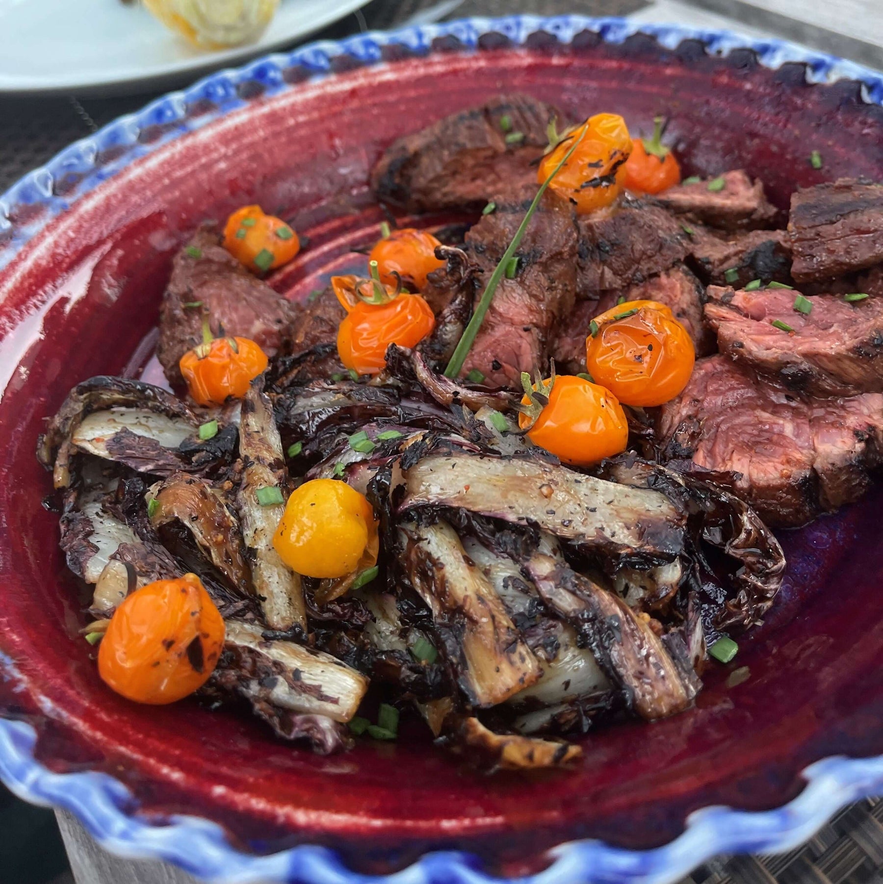 A colorful dish featuring grilled steak, charred vegetables, and tomatoes, showcasing some grilling tips.