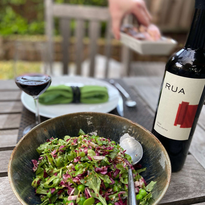 Delicious Our Favorite Spring Salad Recipe in a bowl with wine and table setting.
