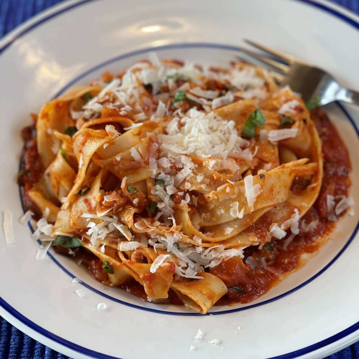Delicious vegan vegetable bolognese recipe served with pasta and topped with grated cheese.