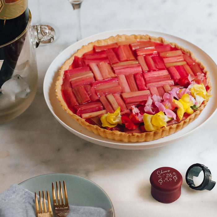 Rhubarb lemon tart recipe beautifully presented with flowers and served with champagne.