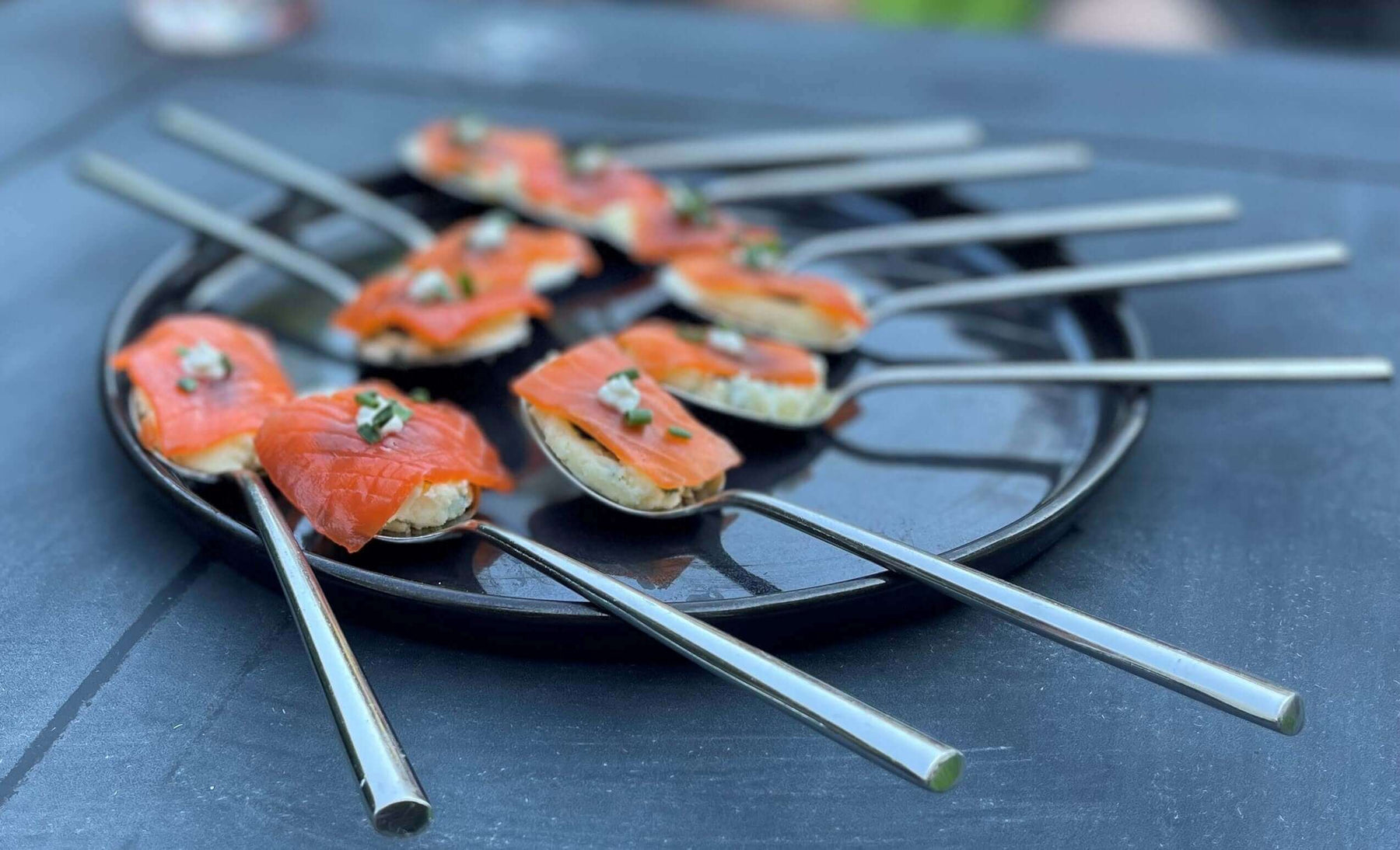 Plate of Smoked Salmon Spoons Recipe garnished with chives on stainless-steel spoons.