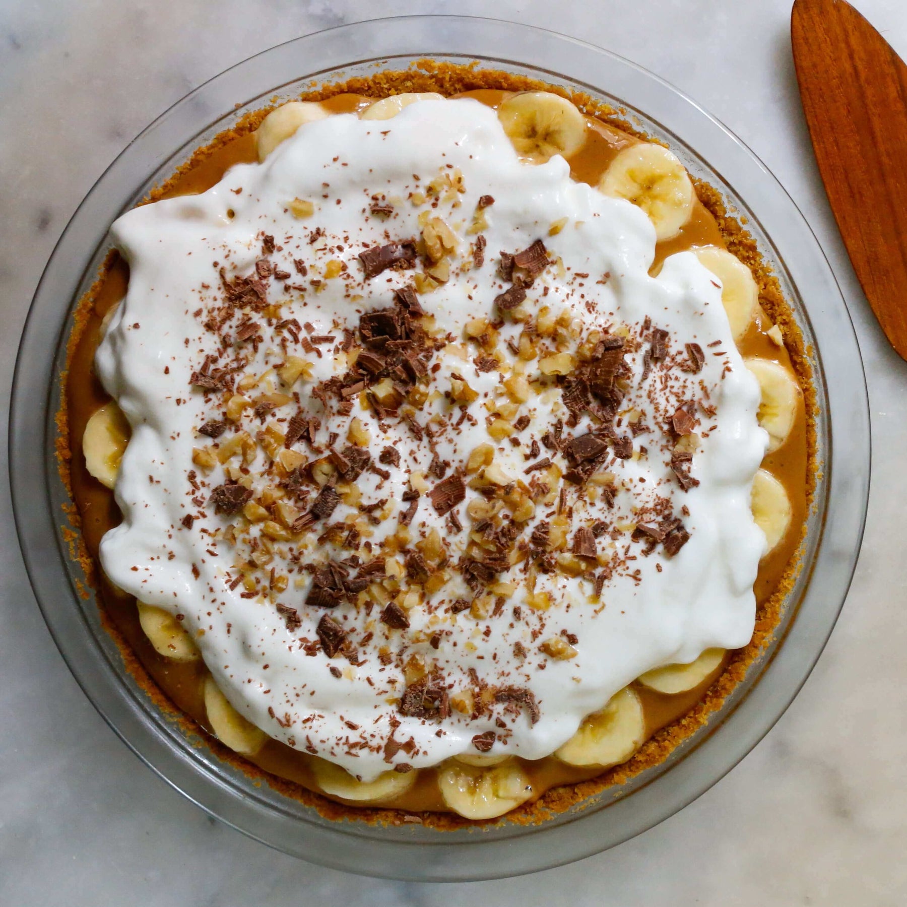 Delicious easy banoffee pie recipe with whipped cream, bananas, and chocolate shavings on top.