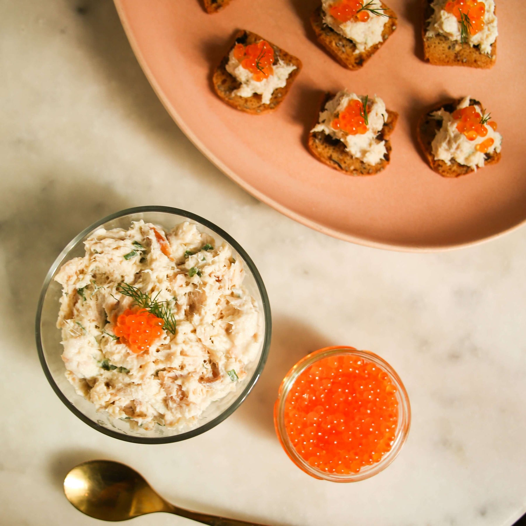 Delicious smoked trout mousse recipe served with toast and caviar on a marble countertop.