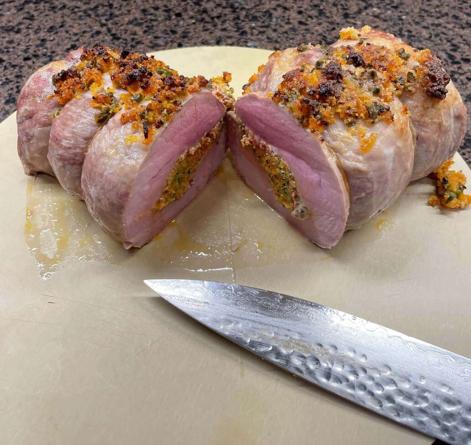 Sliced boneless pork rib roast with borlotti bean recipe alongside a knife on a cutting board.