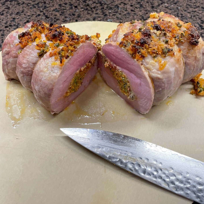 Sliced boneless pork rib roast with borlotti bean recipe alongside a knife on a cutting board.