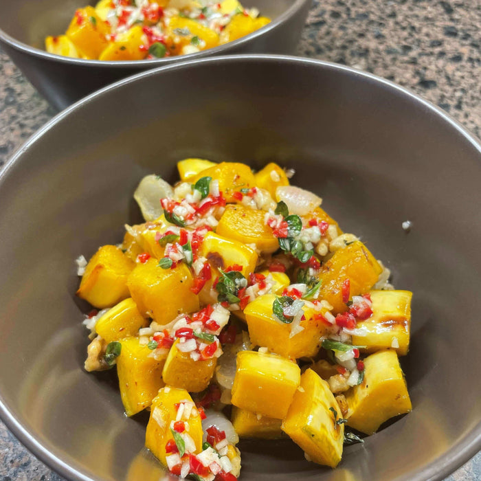 Warm squash salad recipe served in bowls, featuring diced yellow squash and colorful toppings.