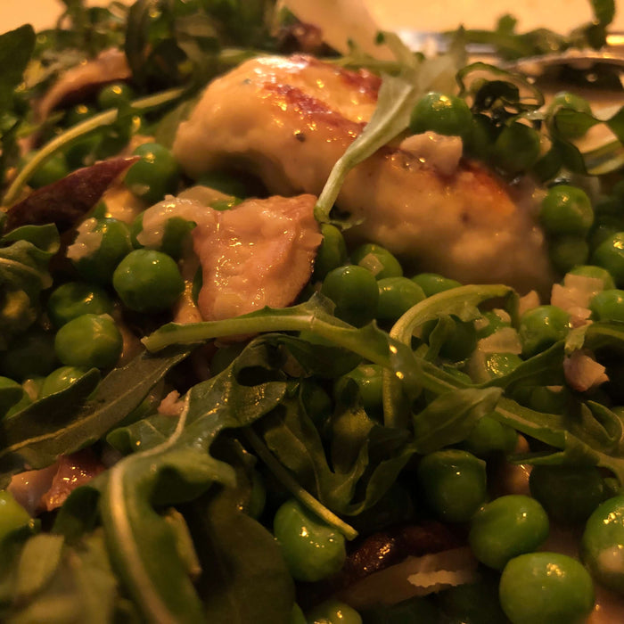Delicious Ricotta Dumplings with Peas Recipe served on a bed of fresh greens and peas.
