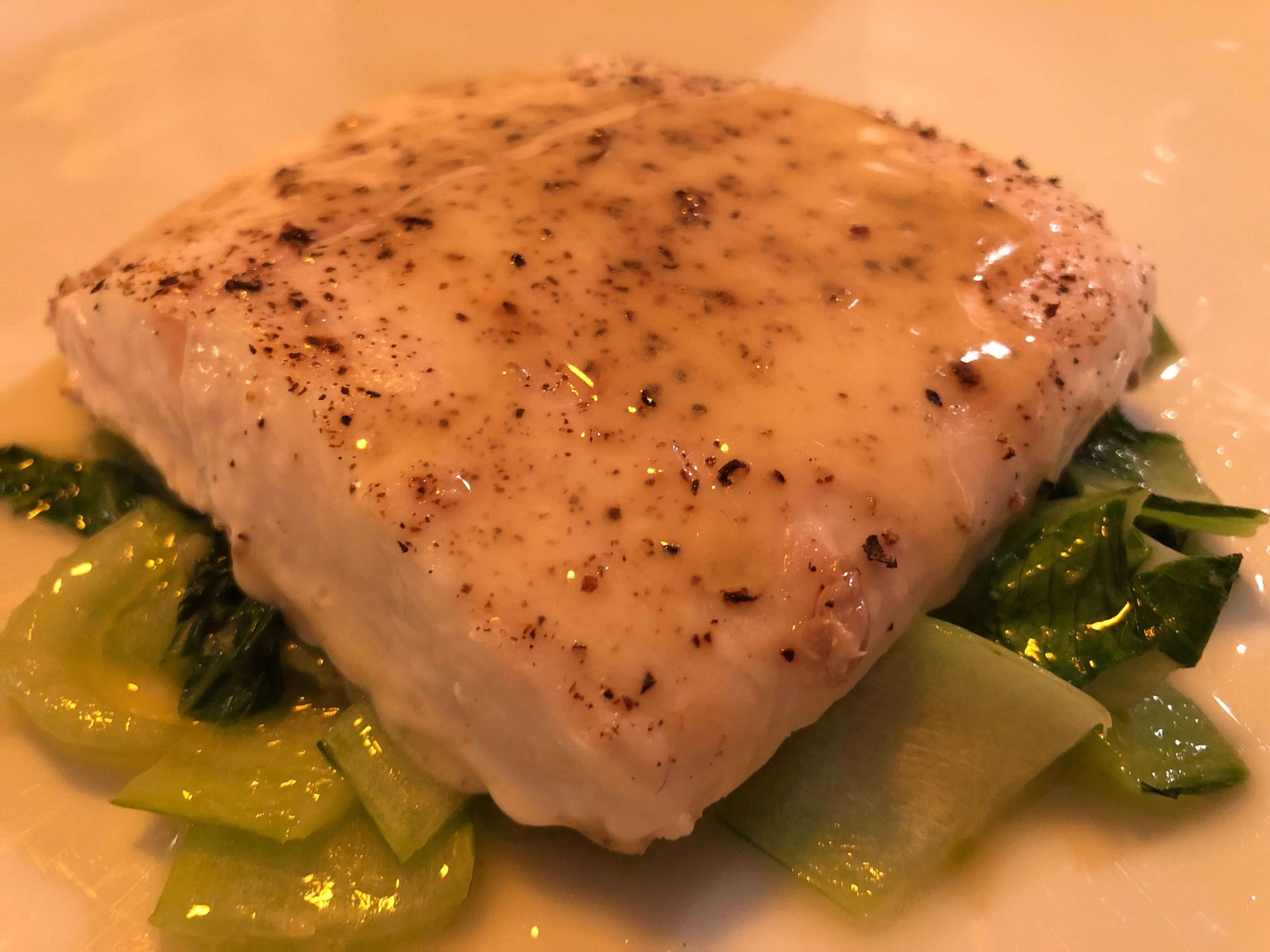 Close-up of Uncle Waltie's Quick Local Halibut Perfection topped with sauce on a bed of greens.
