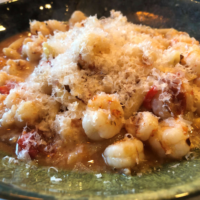 Delicious rock shrimp pasta recipe served with a sprinkle of cheese, showcasing a creamy texture and vibrant colors.