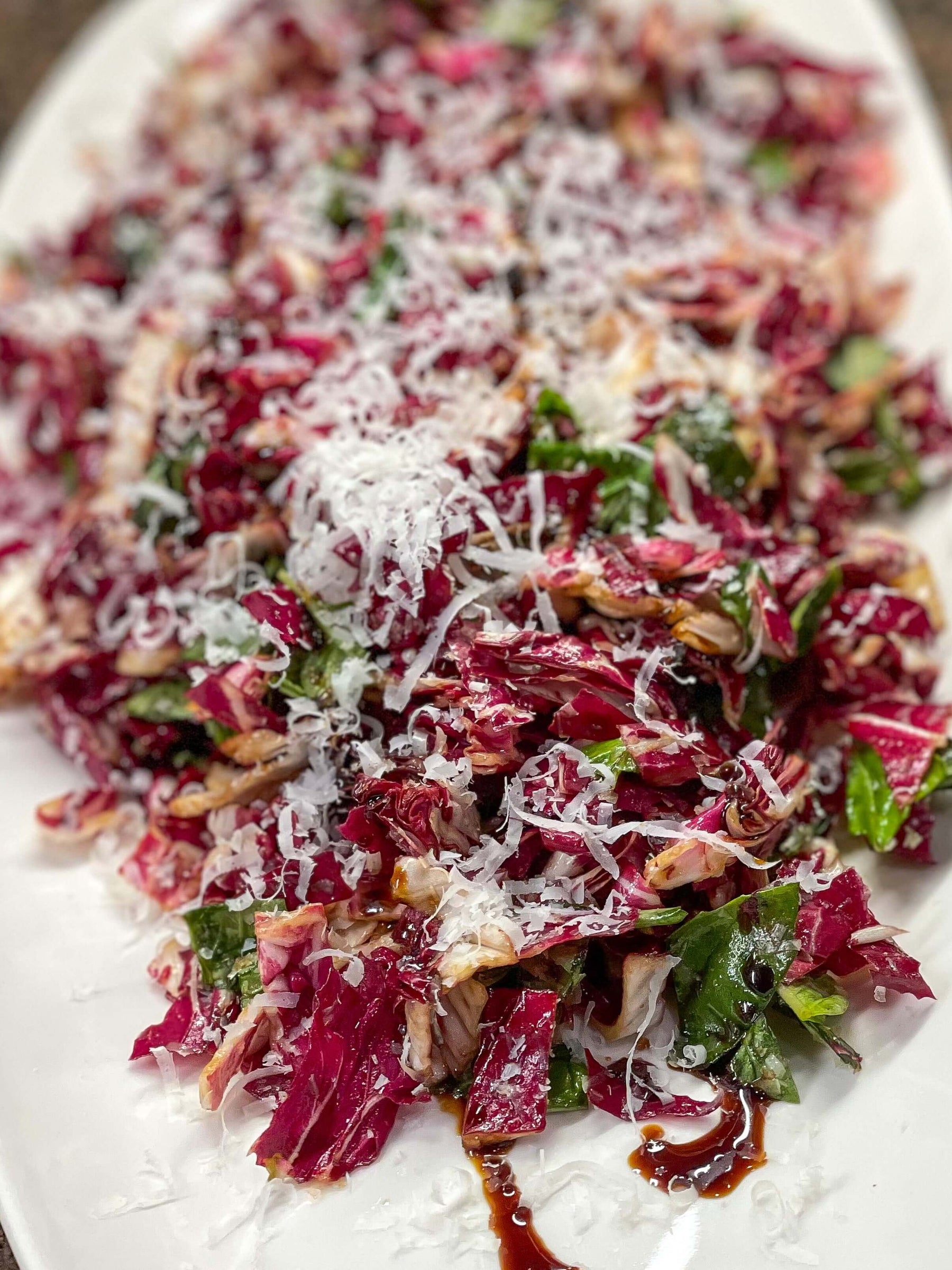 Winter Radicchio Salad with Balsamic Drizzle Recipe served on a white platter, topped with cheese.