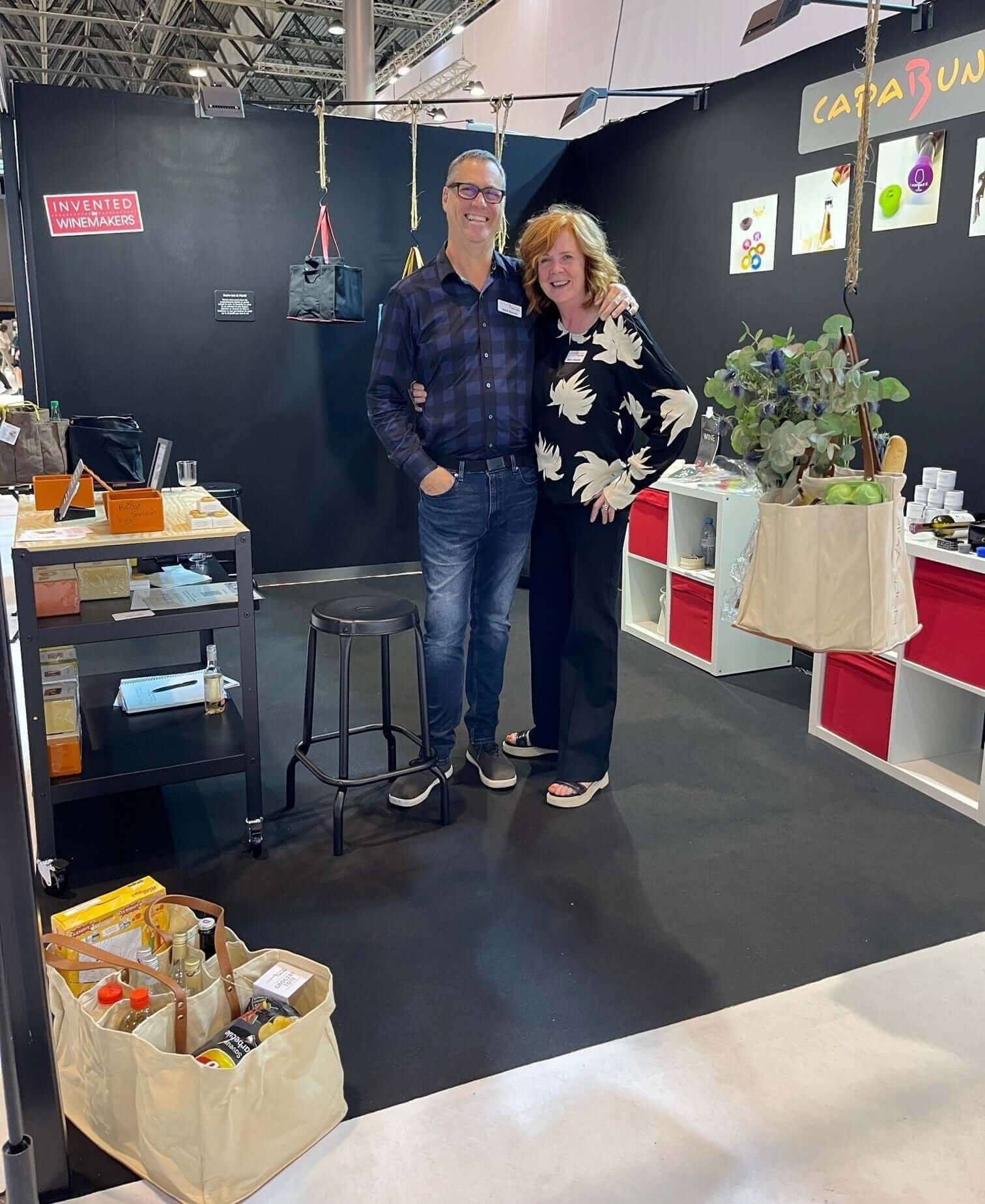 Our first European Show featuring smiling exhibitors in a vibrant booth with products displayed.