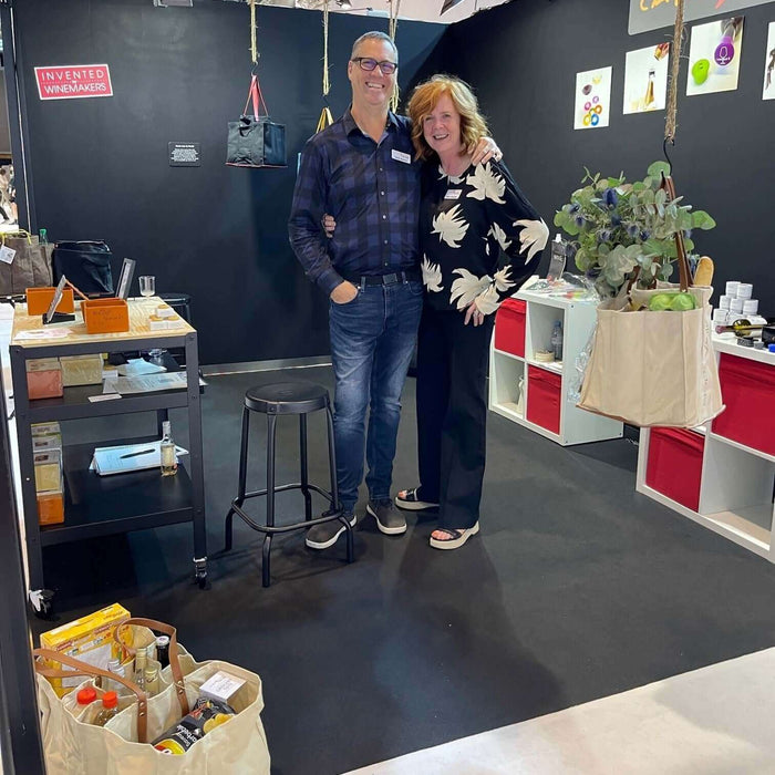 Our first European Show featuring smiling exhibitors in a vibrant booth with products displayed.