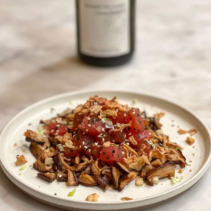 Ahi, Cepe Snack Attack Recipe served on a plate with garnishes and a bottle of wine in the background.