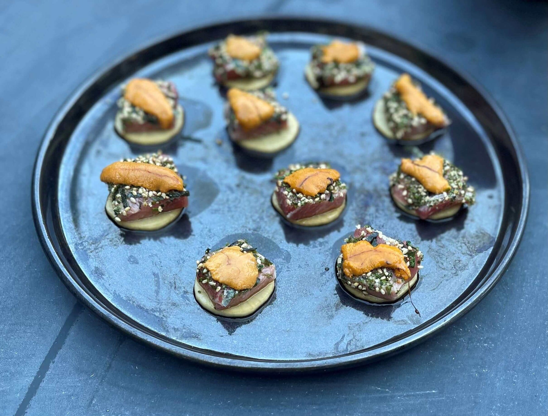 Delicious BL-Uni appetizer recipe served on a black tray, featuring a flavorful seafood topping.