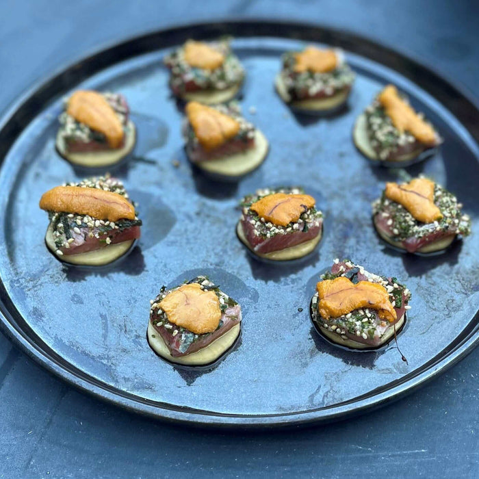 Delicious BL-Uni appetizer recipe served on a black tray, featuring a flavorful seafood topping.