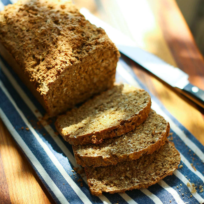 Freshly baked Irish Wheaten Bread Recipe served with sliced pieces on a striped cloth.