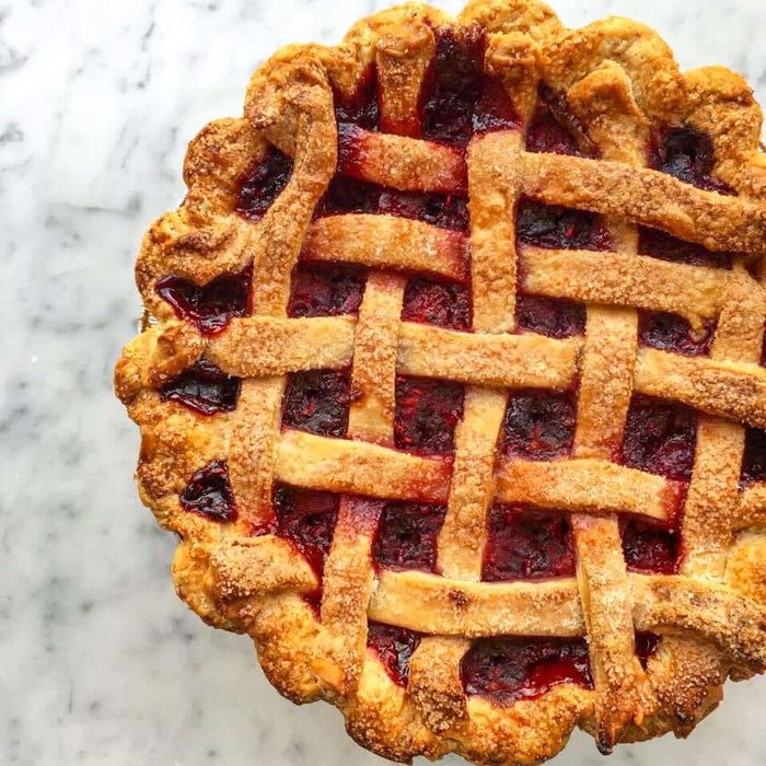 Easy cherry pie recipe with a golden lattice crust and rich cherry filling on a marble surface.