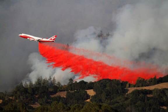 Thanks for all the LOVE as a firefighting aircraft drops red retardant on a wildfire.