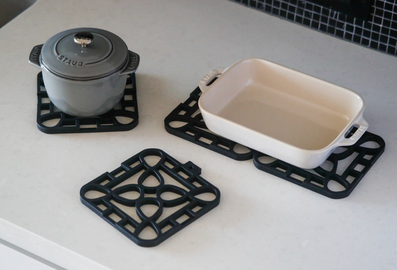 Interlocking silicone trivet protecting a pot and a dish on a modern kitchen countertop.