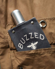 Buzzed Design 120ml canvas flask in a pocket, showcasing rugged fabric and a sleek metal top.