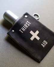 Thirst Aid 120ml canvas flask with silver lid and black cotton cover, perfect for carrying beverages.