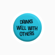 Blue silicone wine cap with the phrase 'Drinks Well With Others' printed on it.