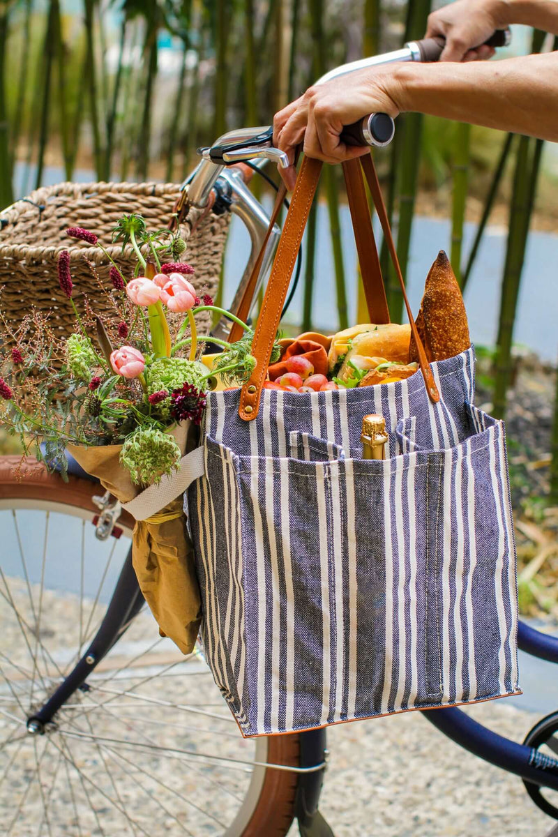 Striped market tote with pockets, stylish design and sturdy handles draped over a bicycle