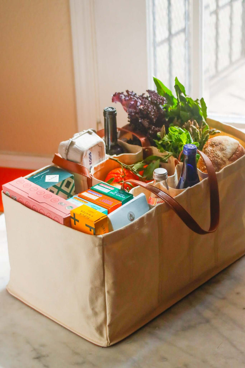 Eco-friendly canvas grocery tote filled with fresh produce, eggs, and beverages on a countertop.