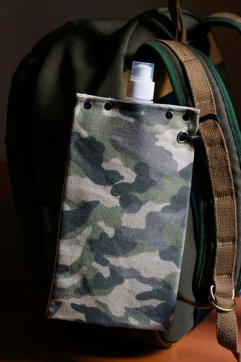 Camouflage canvas canteen attached to a backpack, holding a water bottle for outdoor adventures.