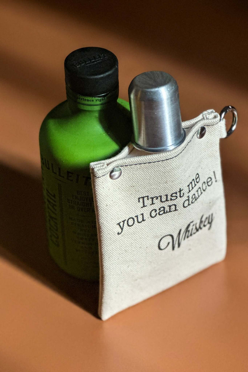 Trust Me 120ml Canvas Flask with whiskey bottle, stylish design with leak-proof liner, ideal for carrying beverages.