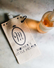 Mother's Helper 750ml canvas canteen with stylish design, next to a bottle of rosé wine on a marble surface.