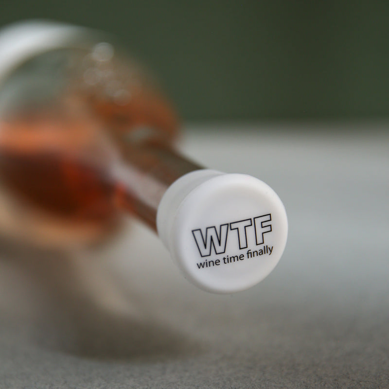 Close-up of a wine bottle cap that reads 'WTF wine time finally', perfect for relaxing moments.