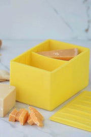CapaBunga Cheese Vault in yellow, storing different cheese blocks and slices on a marble surface.
