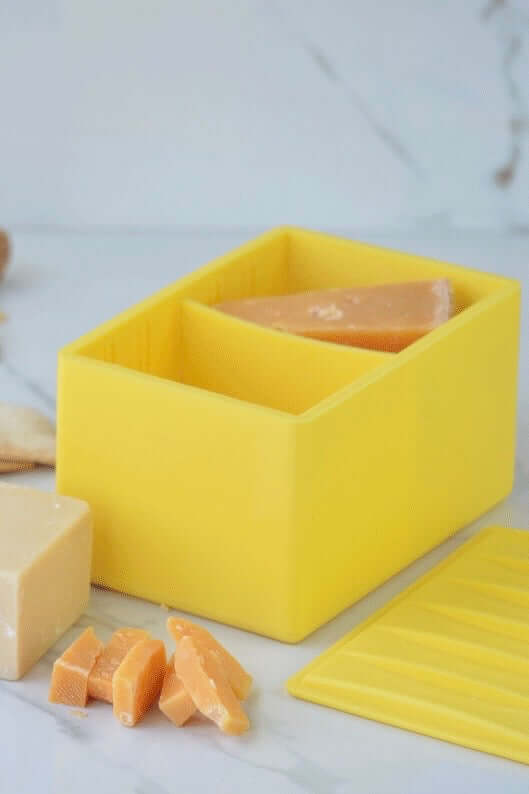 CapaBunga Cheese Vault in yellow, storing different cheese blocks and slices on a marble surface.