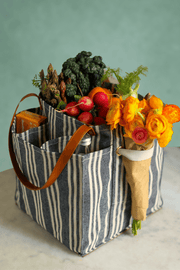 Striped market tote filled with fresh vegetables and flowers, showcasing its spacious pockets and stylish design.