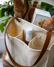 Natural multi-pocket canvas market tote filled with bread, wine, and glassware, showcasing its spacious design.