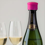 Champagne bottle with pink CapaBubbles stopper and two glasses filled with sparkling wine.