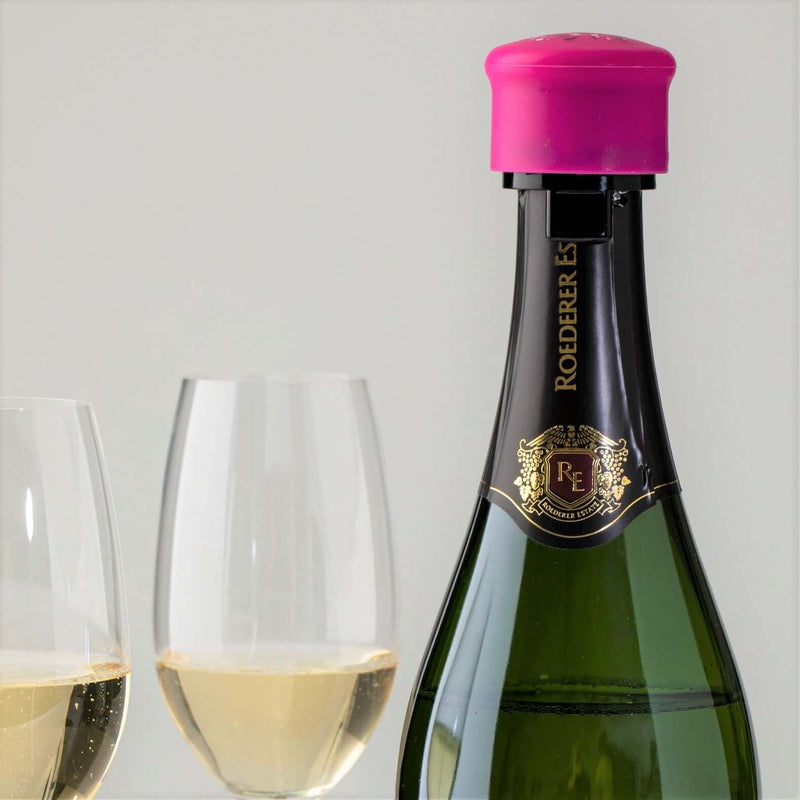 Champagne bottle with pink CapaBubbles stopper and two glasses filled with sparkling wine.