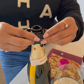 Person using a Champagne stopper on a bottle to preserve sparkling wine.